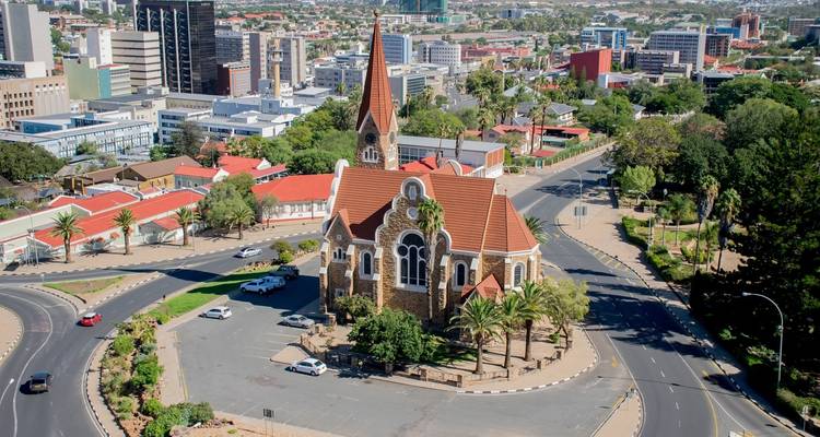 Zicht op een kerk met een spitse dak omgeven door een modern stadslandschap en rotonde.
