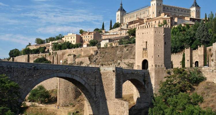 Historische brug met op de achtergrond een heuvelachtige stad.