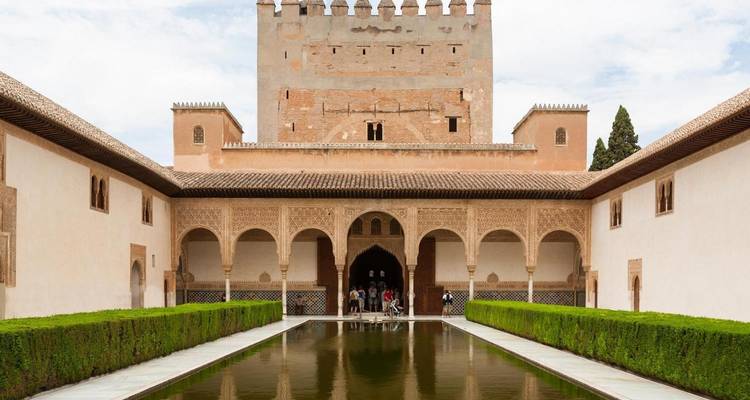 Une cour avec un bassin réfléchissant et l'architecture particulière de l'Alhambra à Grenade.