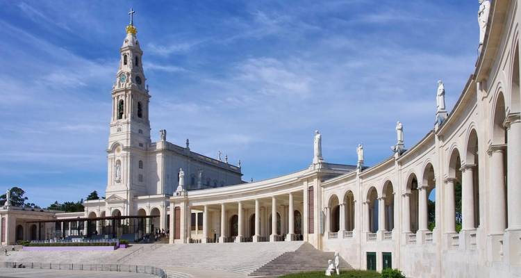 La gran fachada del Santuario de Nuestra Señora de Fátima con estatuas y un cielo despejado.