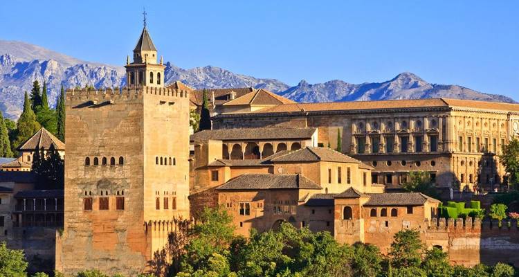 Un gran palacio histórico con montañas como telón de fondo.