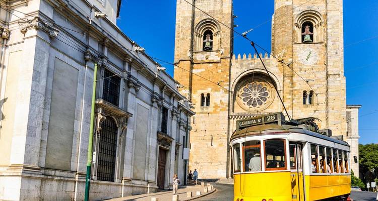 Un tranvía pasa por delante de una catedral histórica bajo un cielo azul despejado.