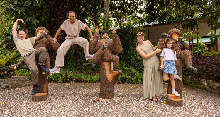 Des enfants posant de manière ludique sur des statues d'orangs-outans dans une attraction de forêt tropicale.