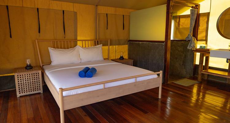 Intérieur simple de tente de glamping avec lit bien fait et planchers en bois.