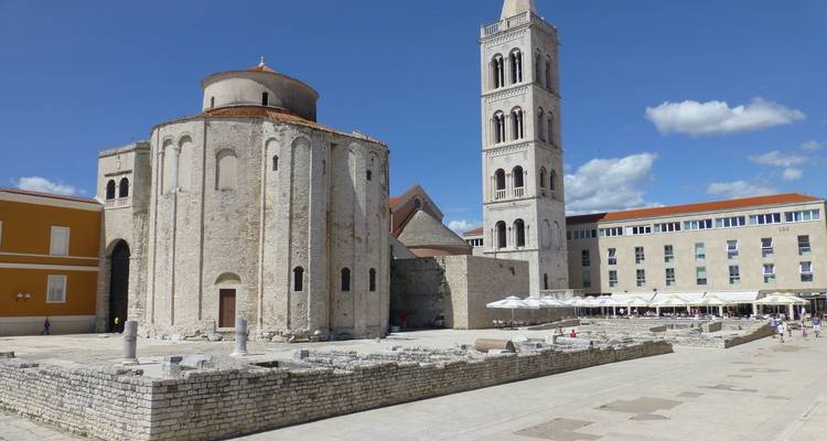 Early medieval circular church with adjoining tall bell tower on a sunlit plaza