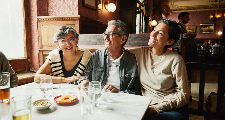 Trois proches partagent des rires autour d'une table en marbre dans une cantina mexicaine vintage et chaleureuse.