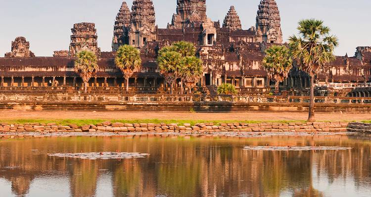 Las majestuosas torres de Angkor Wat se reflejan en un foso tranquilo bajo el resplandor dorado del amanecer en Camboya.