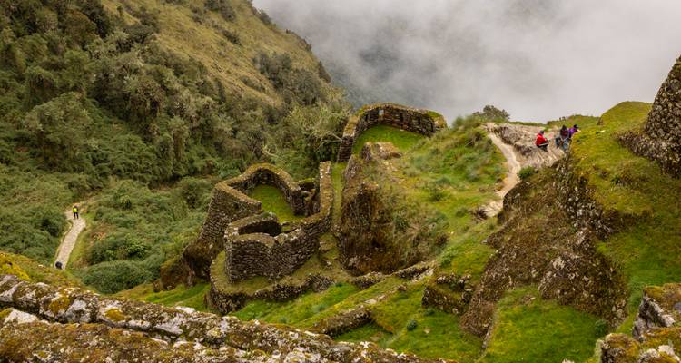 Ruines sur une colline avec des personnes qui explorent.