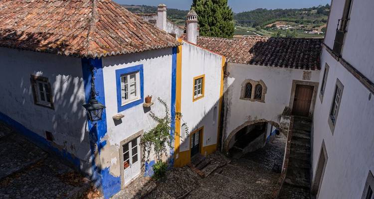 Ruelle pavée étroite bordée de maisons chaulées peintes de rayures bleu vif et jaune