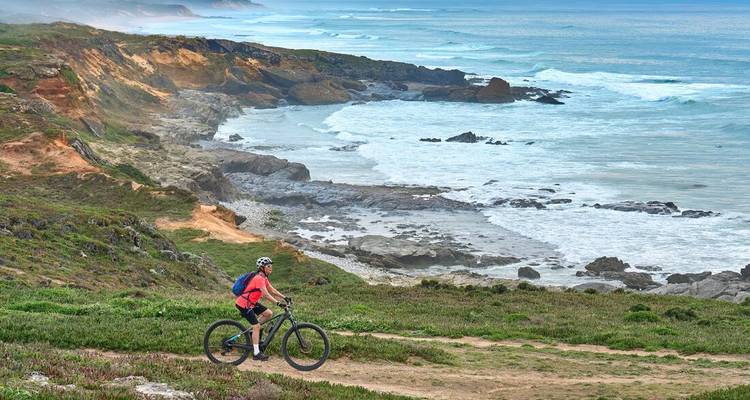 Cycliste de montagne roulant le long d'un sentier accidenté surplombant les falaises de l'Atlantique avec les vagues en dessous