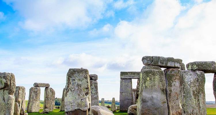 Les massifs piliers de pierre préhistoriques de Stonehenge se dressent sous un ciel bleu vif parsemé de nuages.