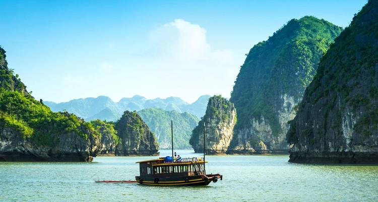 Boat navigating through the limestone karsts of Halong Bay.