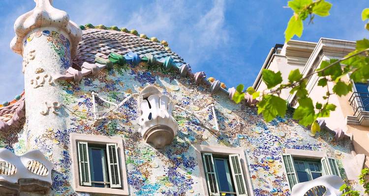 Façade en mosaïque colorée et toit fantaisiste de la Casa Batlló de Gaudí sous un ciel bleu clair.