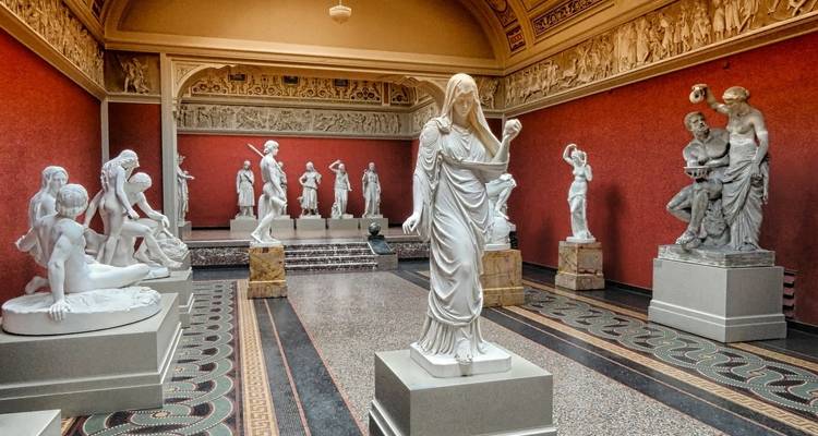 Room filled with white marble statues in a museum setting.