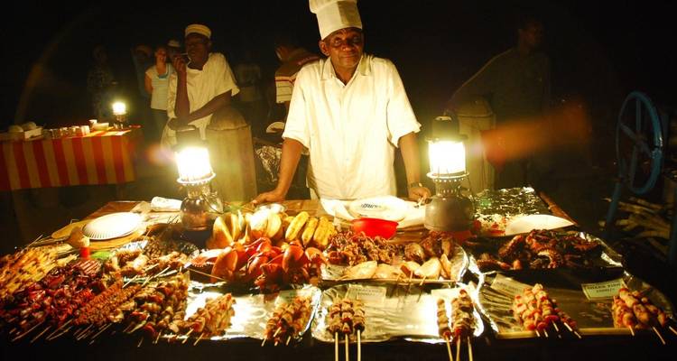 Vendeur de street food la nuit avec divers articles grillés.

Or more naturally in French:

Vendeur de nourriture de rue la nuit avec divers plats grillés.
