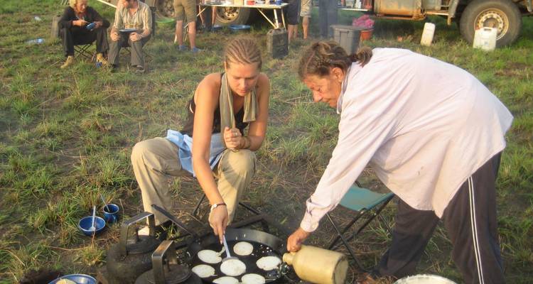 Des gens qui cuisinent et mangent en plein air lors d'un voyage de camping.