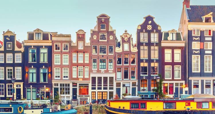 Colorful canal houses and houseboats on water.
