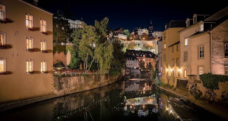 Houses and hills reflected in a nighttime canal.