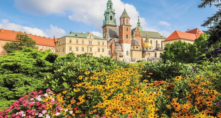 Château du Wawel à Cracovie avec des jardins colorés au premier plan.