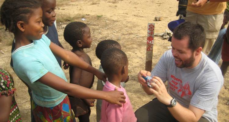 Grupo de niños con un adulto interactuando alegremente al aire libre.