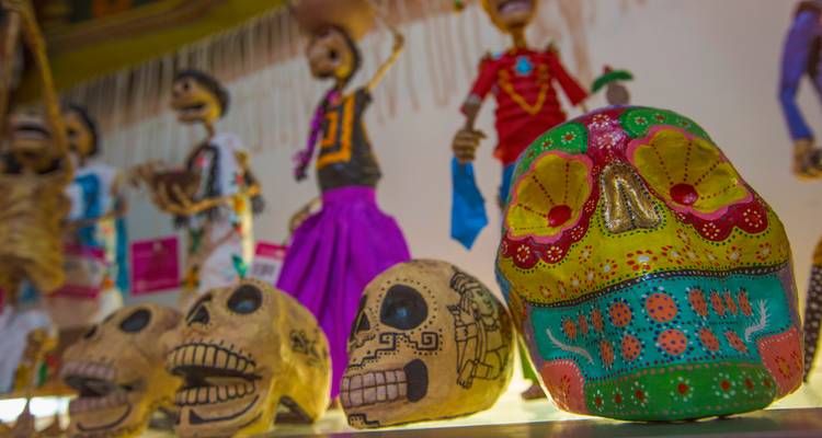 Colourful painted Day of the Dead skulls and puppets displayed in a craft shop.