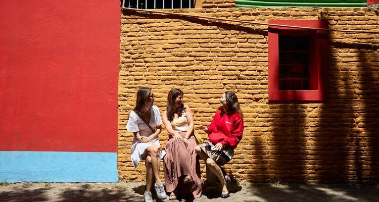 Trois femmes assises contre des murs colorés à Buenos Aires.