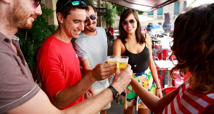 Grupo de amigos brindando con bebidas en una cafetería al aire libre.