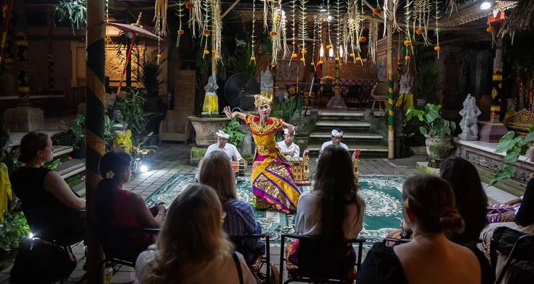 Spectacle de danse balinaise en soirée sur une scène décorée avec un public de voyageurs regardant attentivement.