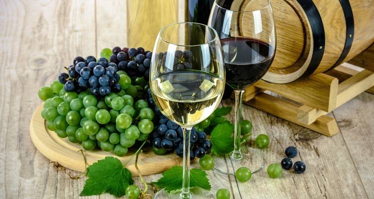 Uvas y copas de vino sobre una mesa de madera con un barril.