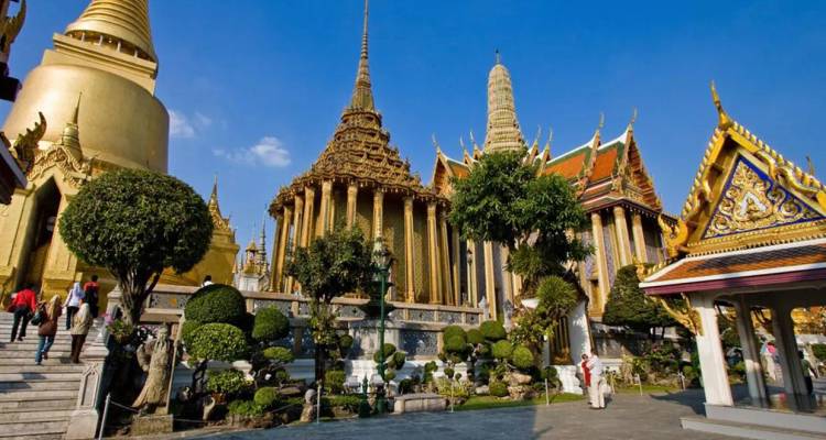 Stupas et temples dorés ornés du complexe du Grand Palais de Bangkok sous un ciel bleu dégagé.