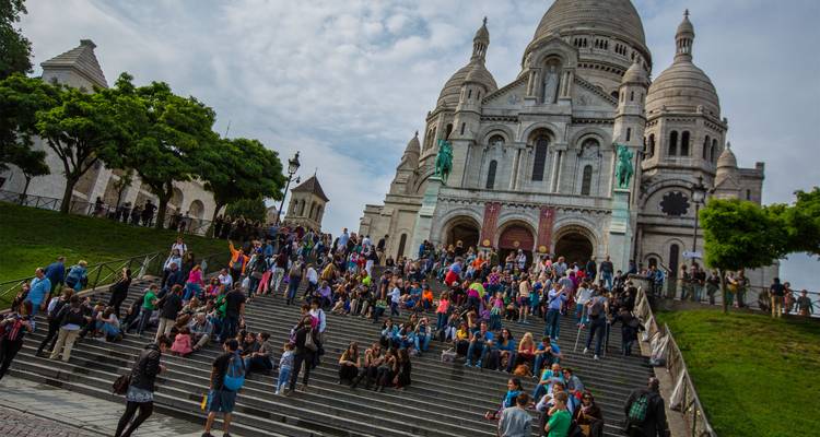 Large crowd sitting on the steps before the Sacré-Cœur Basilica in Paris.