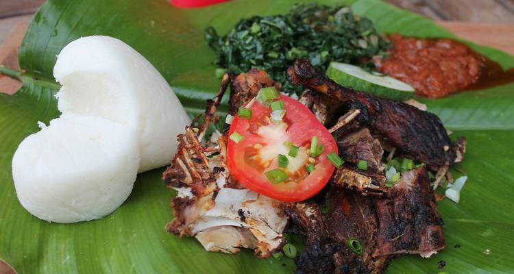Comida africana tradicional con carne a la parrilla, tomate, verduras y sadza en hoja de plátano