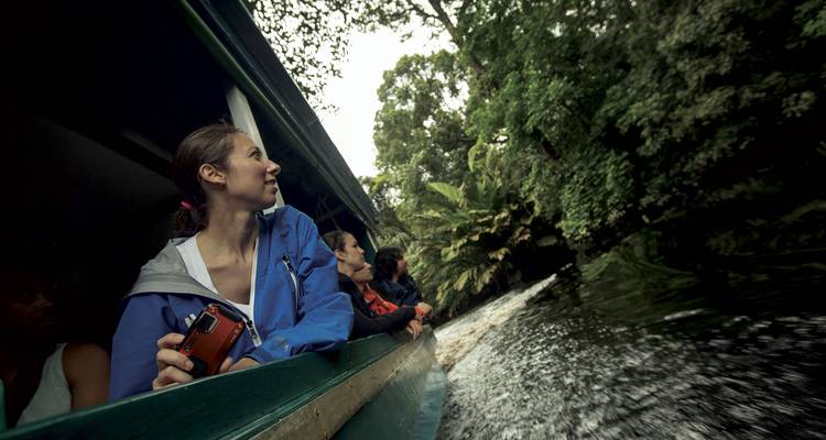Les voyageurs se penchent hors d'un bateau à moteur alors qu'il glisse à travers une voie navigable entourée d'une jungle luxuriante.