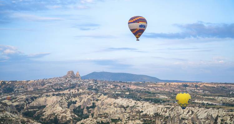 Hot air balloons floating over rocky landscape.