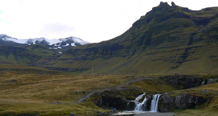 Cascada y montañas nevadas al fondo.