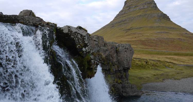 Montaña Kirkjufell y una cascada bajo un cielo nublado.