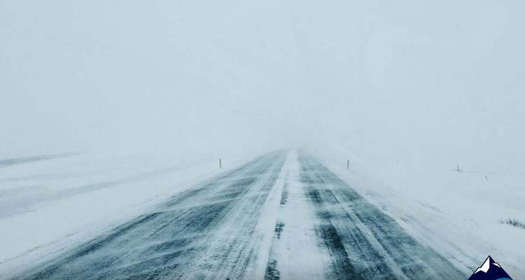 Carretera cubierta de nieve durante una ventisca.
