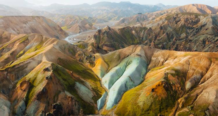 Paysage de montagne vibrant avec des ruisseaux visibles et des pentes de différentes couleurs.