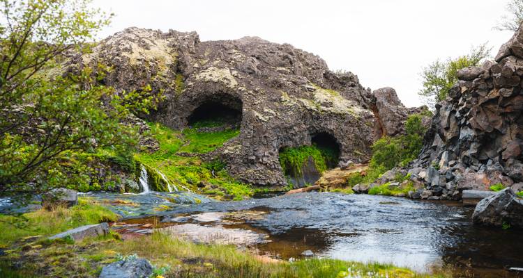 Petit ruisseau coulant à travers un terrain rocheux avec des grottes moussues.