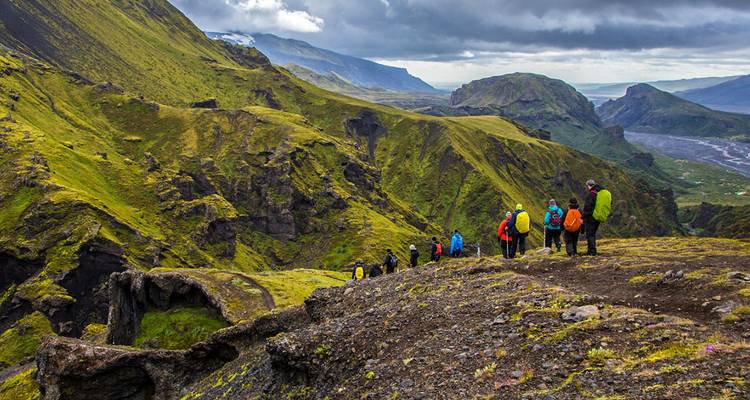 Hikers in colorful outfits trekking through a verdant valley.