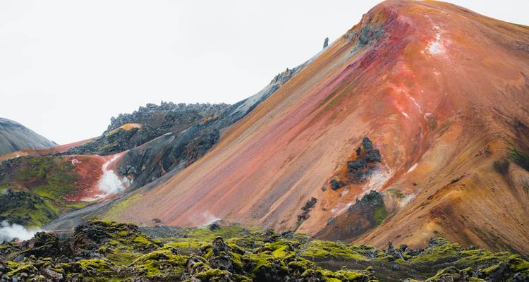 Gros plan d'une pente de rhyolite rouge et orange avec un premier plan de lave mousseuse.