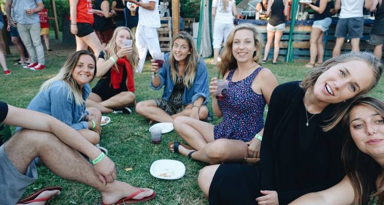 Group of friends sitting on grass, enjoying a picnic.
