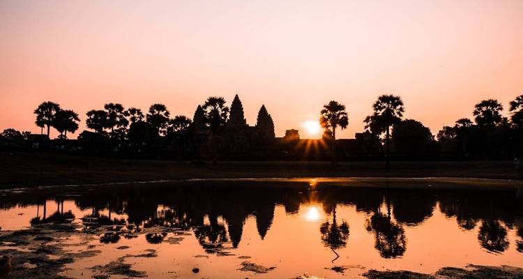 Vue du coucher de soleil d'un temple se reflétant sur l'eau.