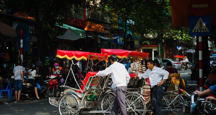 Vendedores ambulantes con triciclos tradicionales en una calle concurrida.