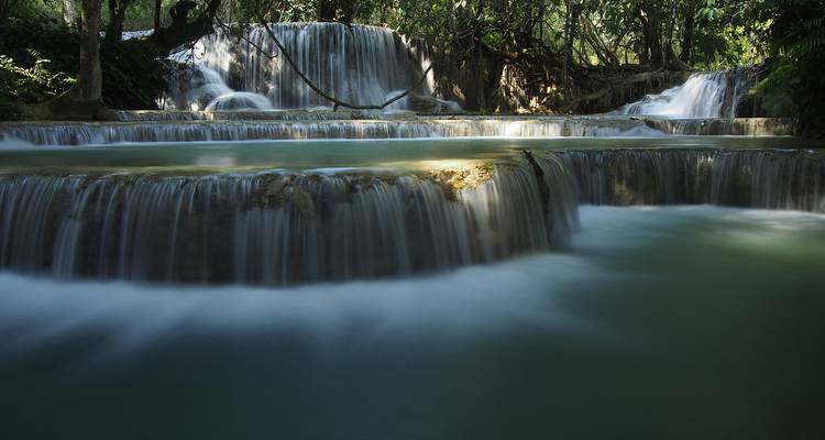 Les cascades soyeuses des chutes de Kuang Si s'écoulant dans des bassins turquoise dans un cadre de jungle.