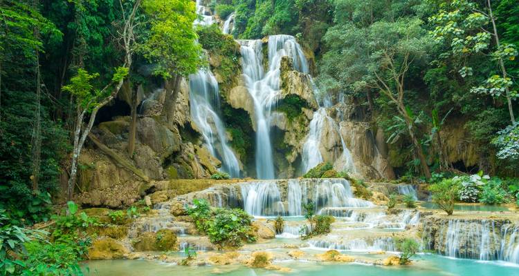 Vue panoramique des spectaculaires chutes de Kuang Si se jetant dans la forêt tropicale vers des bassins d'eau émeraude.