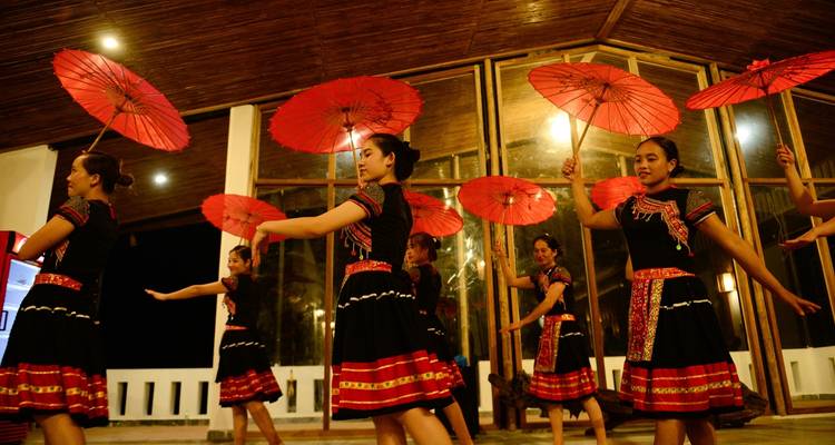 Artistes en tenue traditionnelle avec des parapluies rouges.