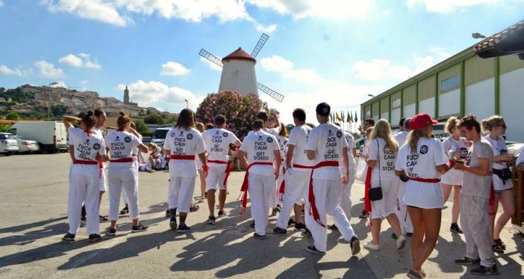 Des personnes en tenue de festival avec un moulin à vent en arrière-plan.