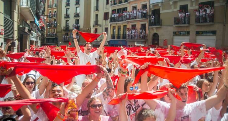 Grande foule agitant des bandanas rouges lors d'un festival de rue.