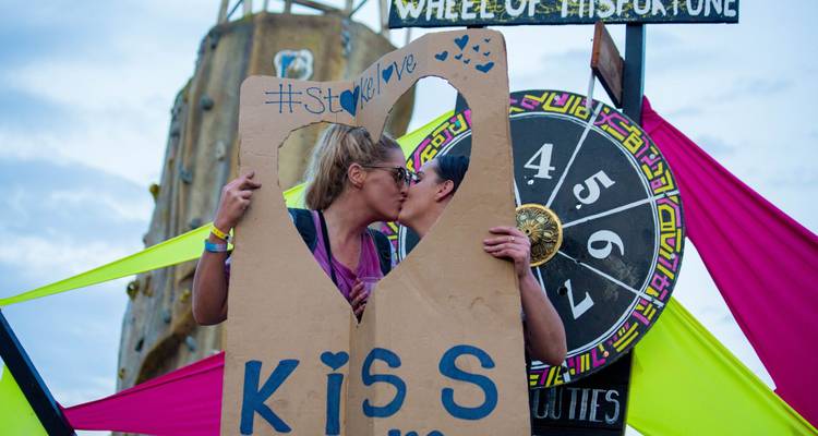 Couple qui s'embrasse derrière une découpe lors d'un festival avec roue chromatique.